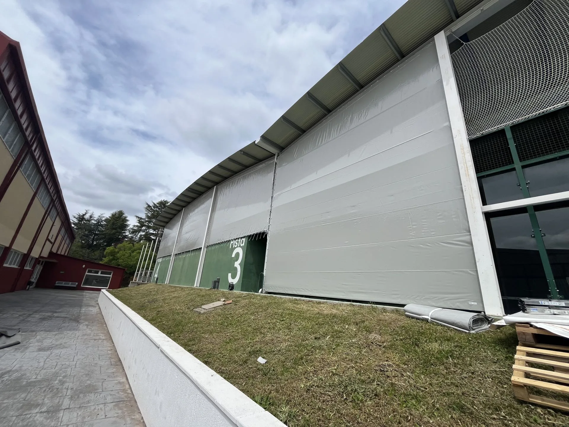 Fachada textil sobre pabellón con cerramiento lateral