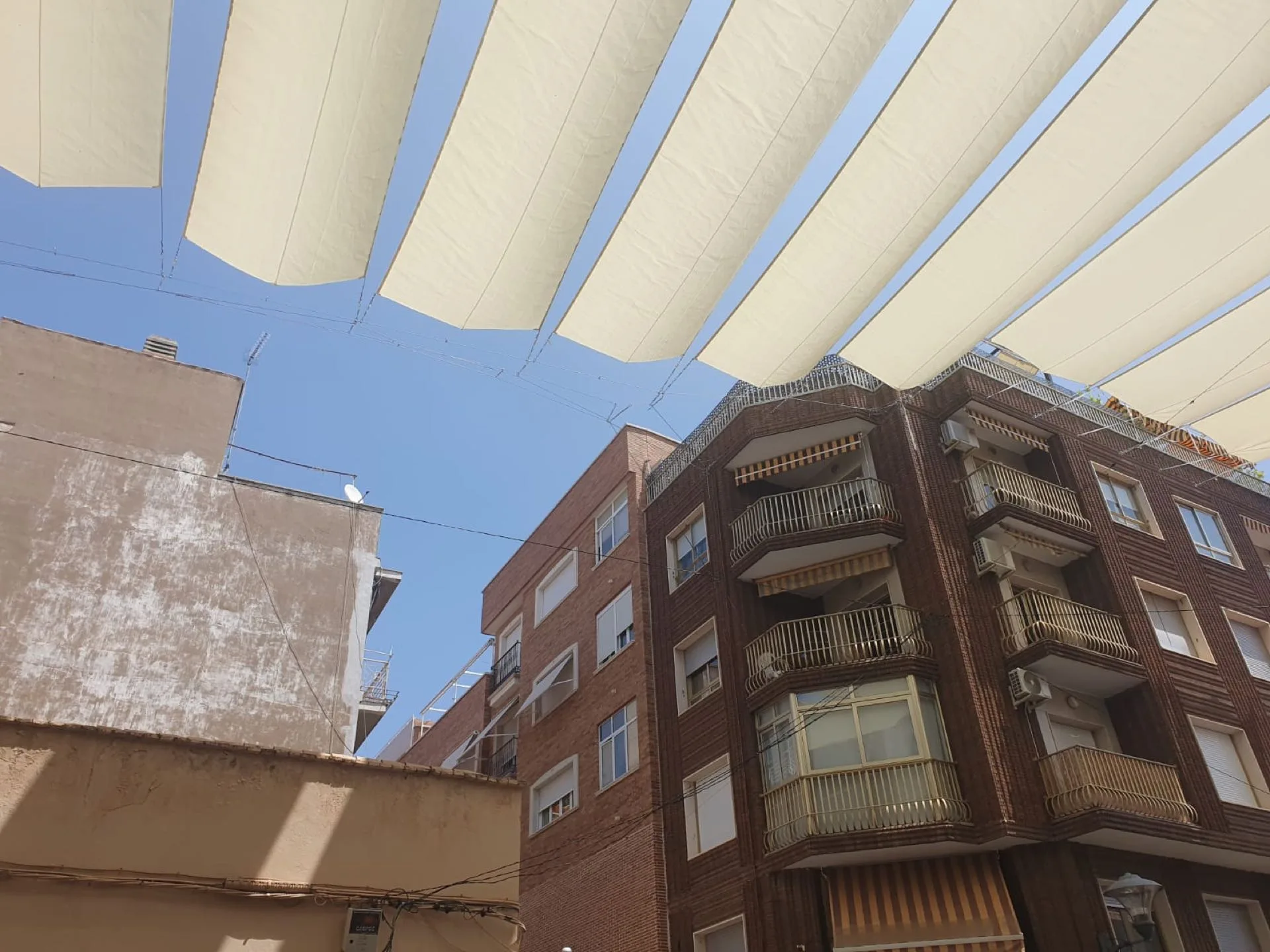 Entoldado blanco de fajas continuas entre edificios