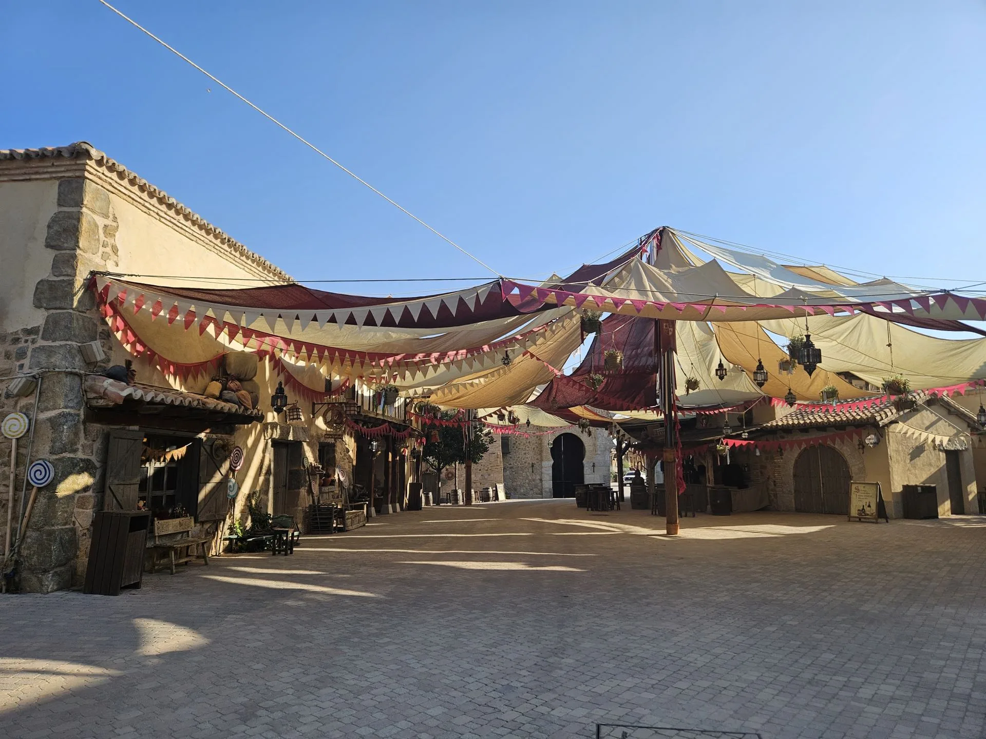 Plaza de pueblo con entoldado decorativo y farolillos