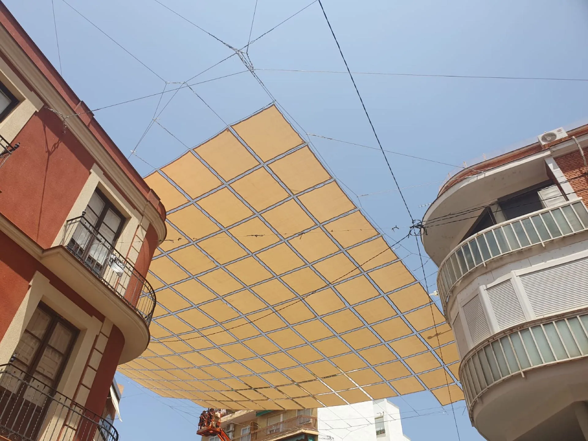 Entoldado amarillo suspendido entre fachadas urbanas