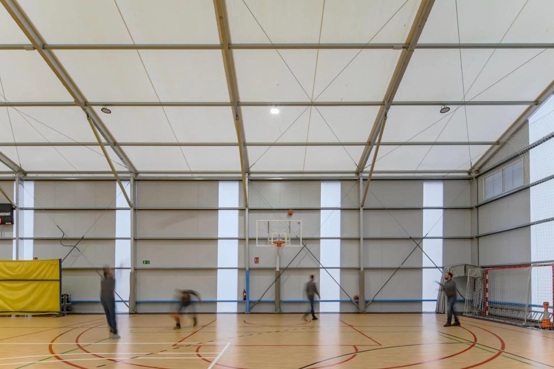 Jugadores entrenando baloncesto dentro de pabellón deportivo desmontable