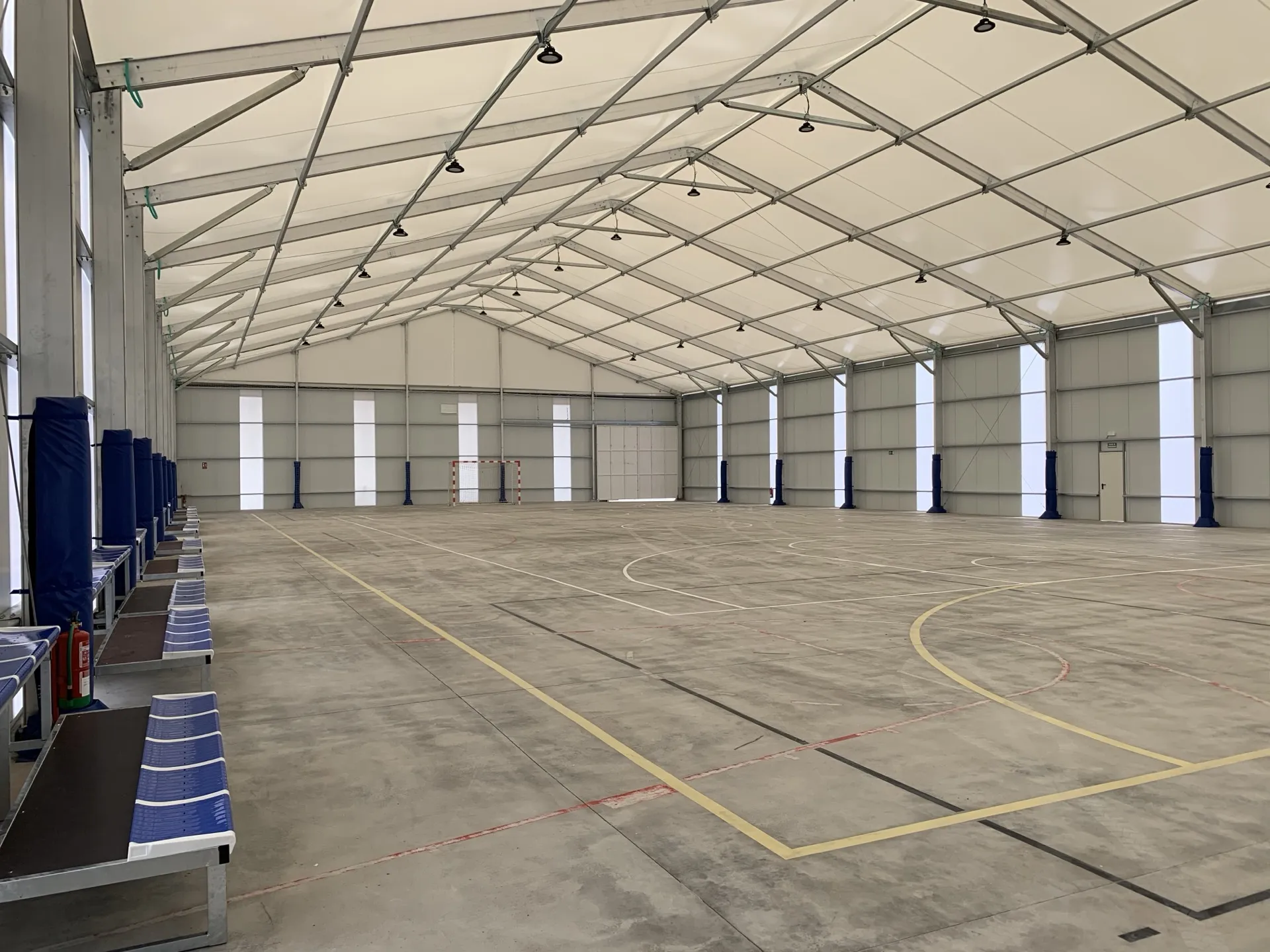 Interior de pabellón deportivo desmontable con gradas y techo translúcido
