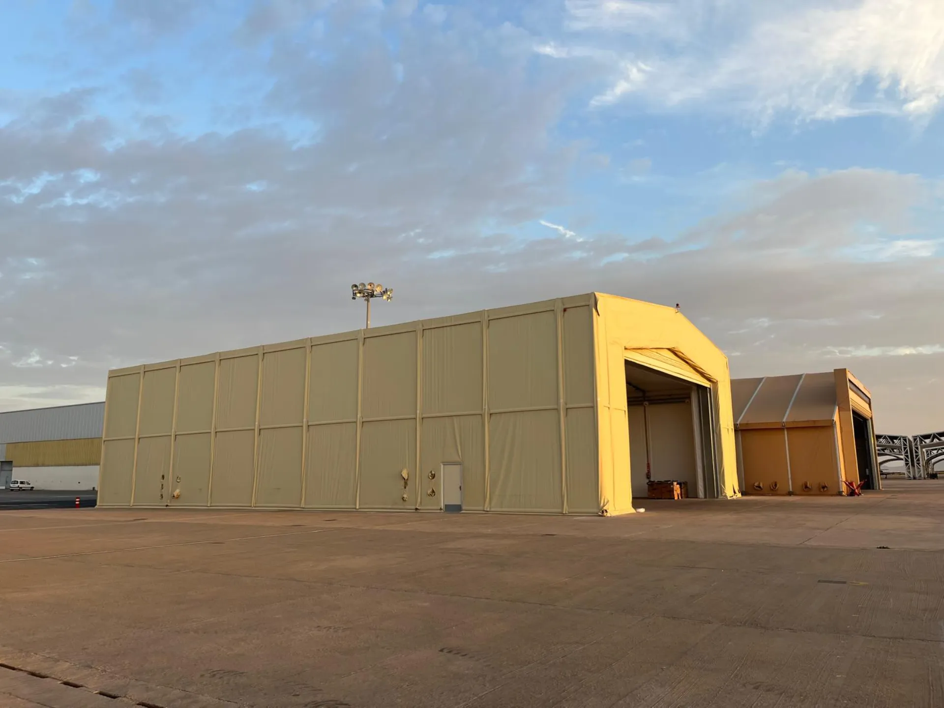 Hangar militar desmontable de color arena en base aérea al amanecer